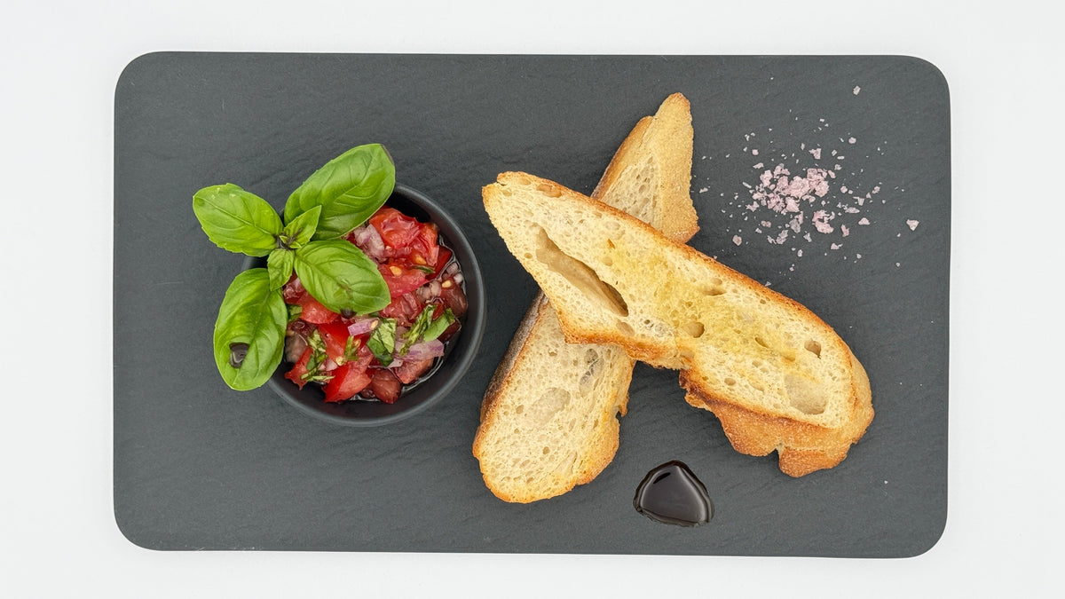 Bruschetta selbst-gemacht mit reifen Tomaten, Basilikum, roter Zwiebel, Olivenöl, Meersalz und Tellicherry Pfeffer auf geröstetem Brot
